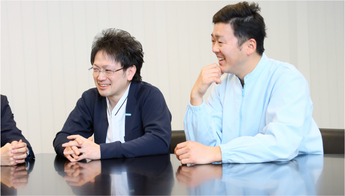 写真:テーブルの肘をつき、話を聞いている様子。